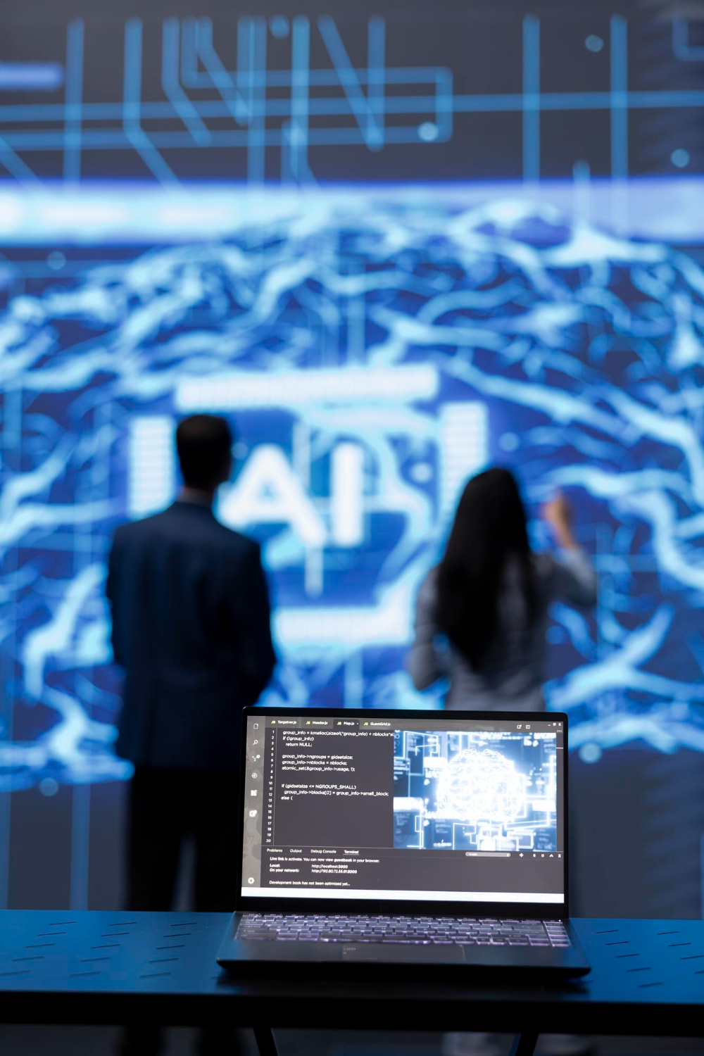 Two people in front of a large AI visualisation, with a laptop in the foreground