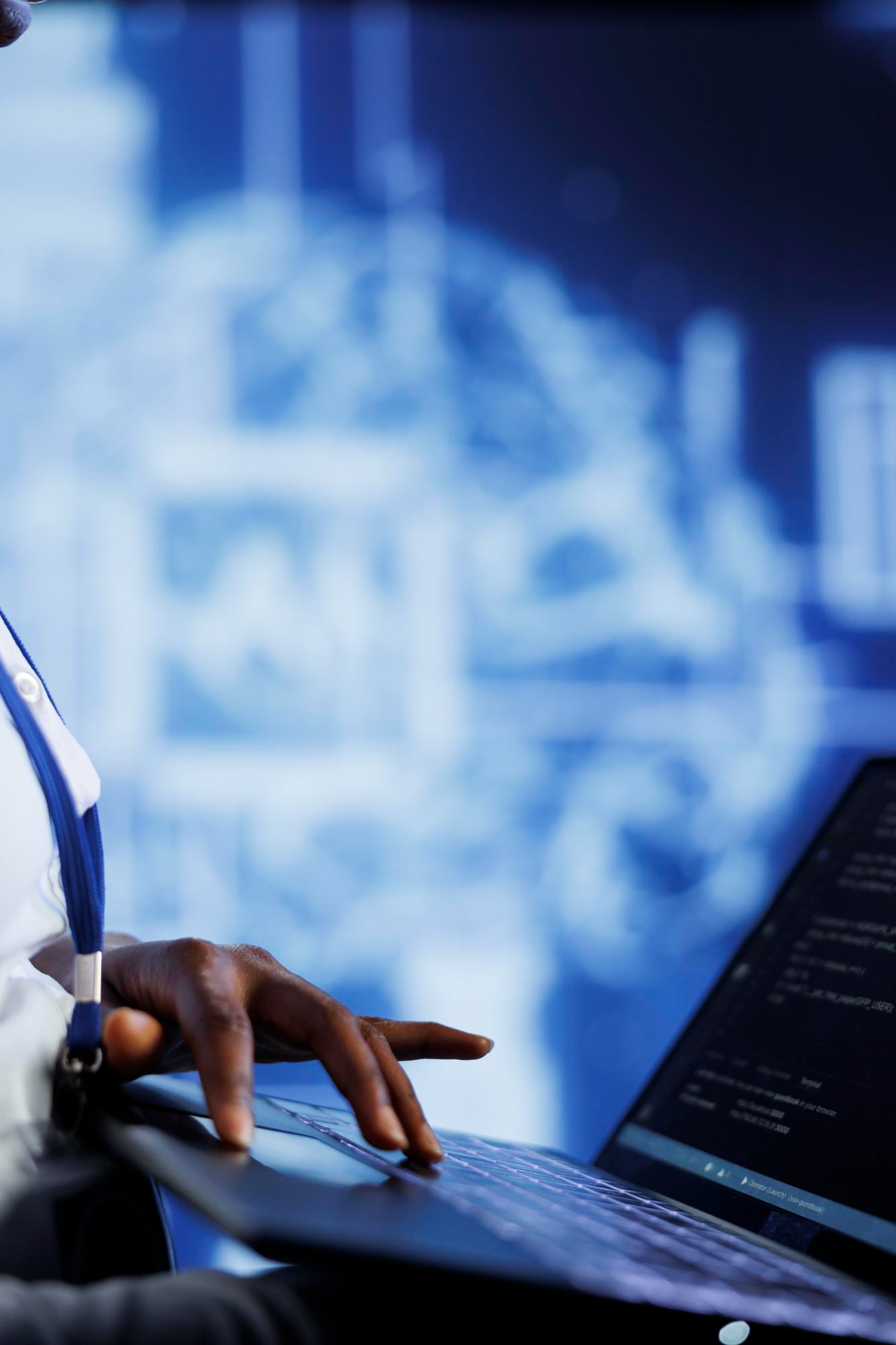 A person typing on a laptop in front of a blue AI display